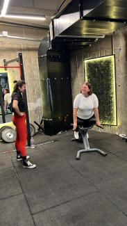 Bir spor salonunda ters mekik aletinde orta yaşlarda, spor giyimli bir kadın (Sevgi Mart Göcen) yan tarafında elleri belinde duran spor giyimli bir kadınla (Spor hocası Ceyda Barut) karşılıklı gülümsüyorlar.