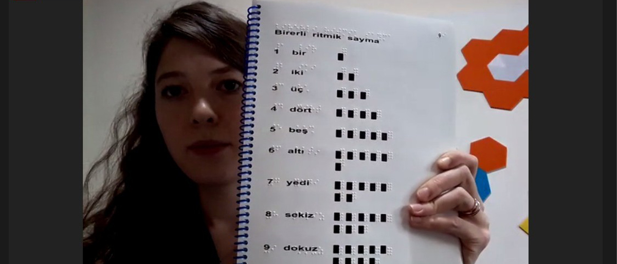Braille ve mürekkep baskı bulunan bir sayı kitabı gösteriliyor.