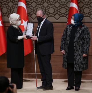 Olgun Yılmaz Ödül’ü sağındaki Sayın Emine Erdoğan’la birlikte tutuyor. Sol tarafında da Sayın Zehra Zümrüt Selçuk var.